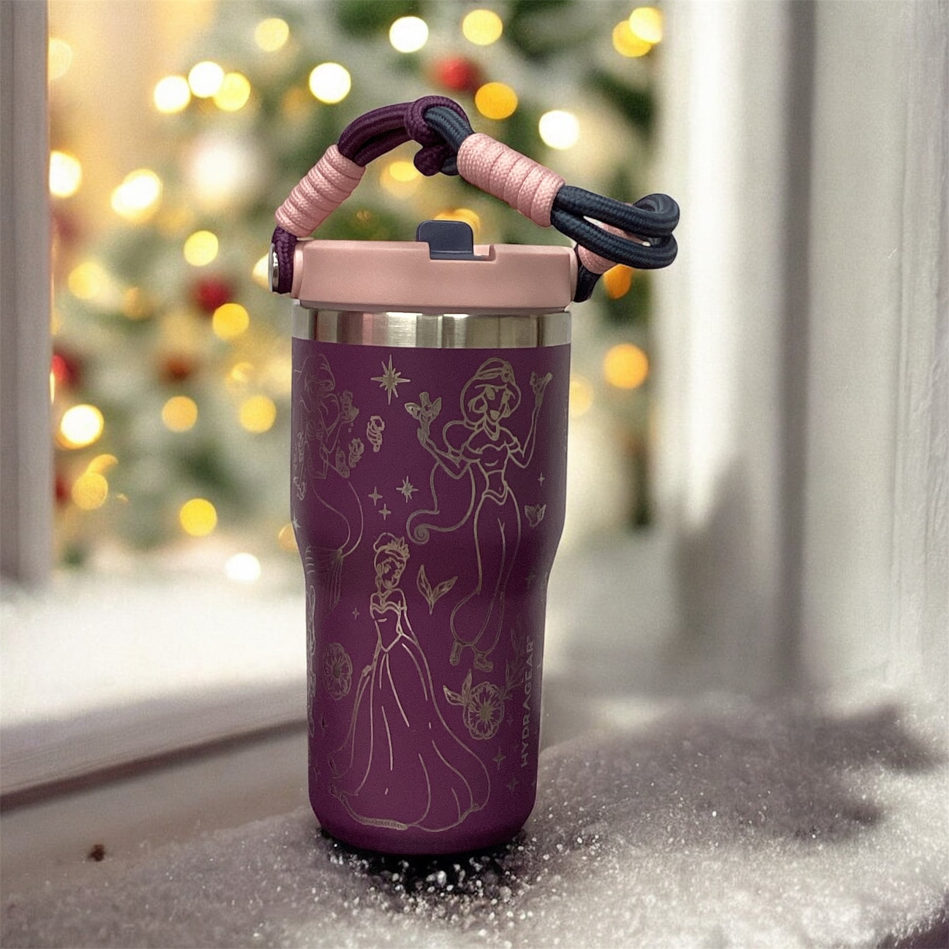 Purple tumbler with princess design on a windowsill with a blurred Christmas tree in the background